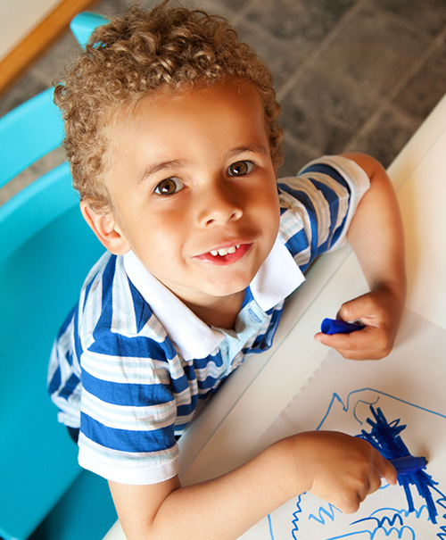 Young boy with curly hair drawing 