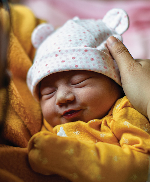A newborn baby sleeping peacefully while being gently cradled.