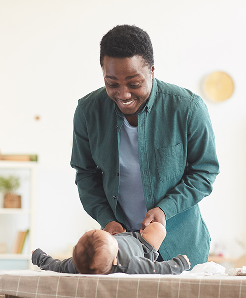 A smiling father baby lying on a changing table in a bright, cozy room