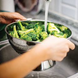 Washing broccoli under running water